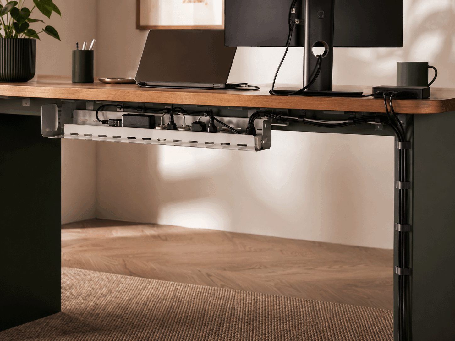 A home-office desk with an under-desk tray, power board and cables routed down the rear leg